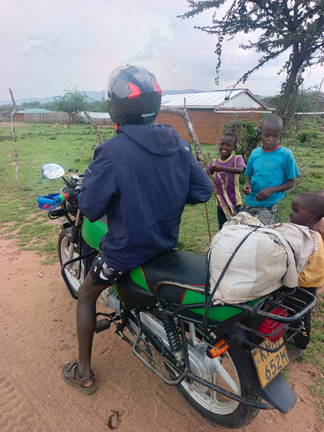An ITF volunteer on a motorbike stopped to talk with children in a rural community