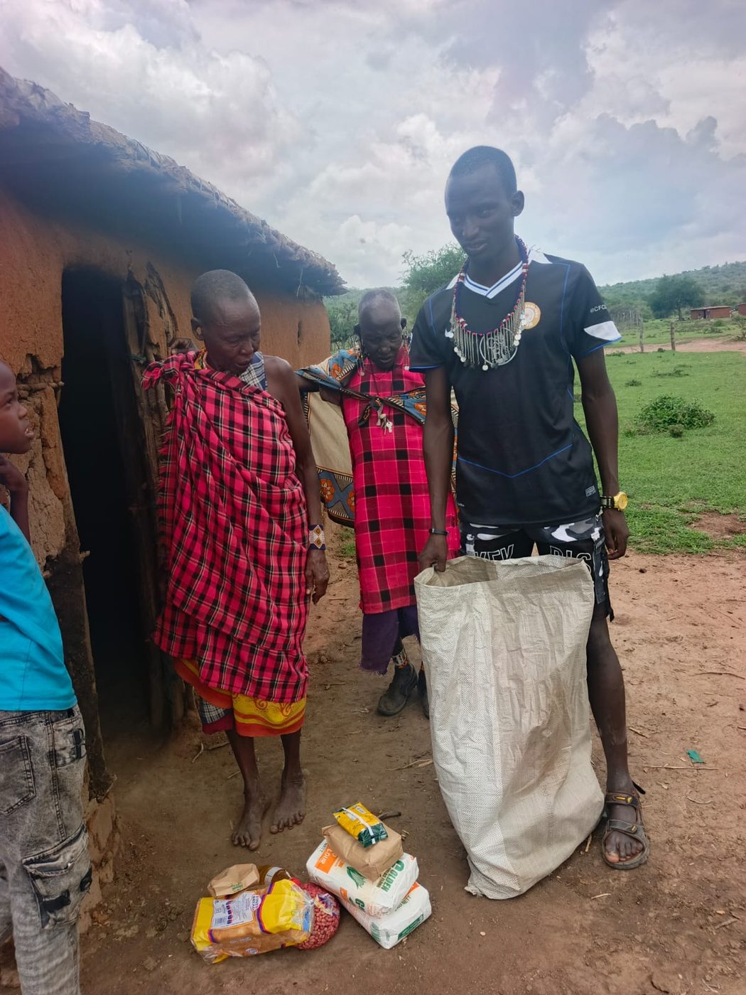 An ITF volunteer delivering food supplies to two elderly women outside their home